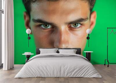 An expressive face with intense eyes stands out against the lush green backdrop. Wall mural