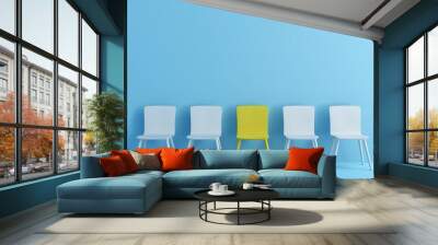 outstanding yellow chair among light blue chair. Chairs with one odd one out in light blue color room. Wall mural