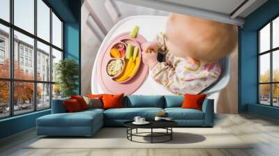 Baby sitting in a baby chair and eating a baby lead weaning meal  Wall mural