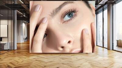 Beautiful young woman with clean perfect skin. Portrait of beauty model with natural nude make up and and hand with manicure touching face. Spa, skincare and wellness. Close up Wall mural