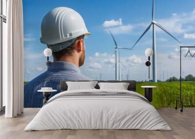 Engineer wearing a hard hat in front of a wind farm Wall mural