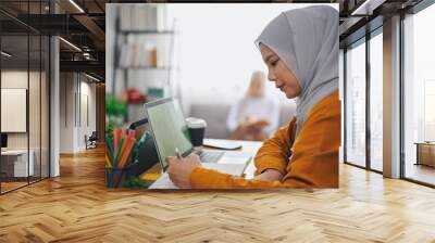 Islamic woman wearing hijab headscarf studying online with laptop. Wall mural