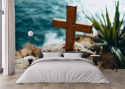 Wooden Cross Stands on Rocky Coastline Overlooking Tranquil Ocean With Vibrant Greenery, Symbolizing Faith and Serenity Near the Water Wall mural