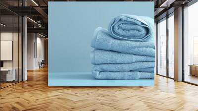 Light blue spa towels pile, bath towels lying in a stack on light blue peaceful background with copy space. Wall mural