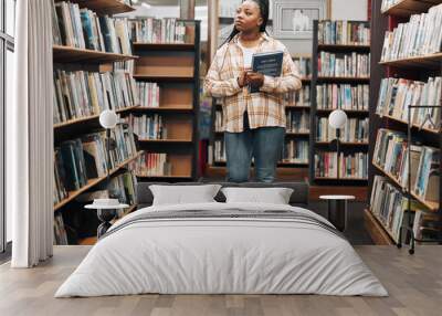 Search, university or black woman in a library for books, educational knowledge or research on a college campus. Scholarship, future or African school student walking or shopping in retail book store Wall mural