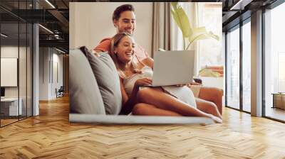 Together is the best place to be. Shot of a young couple using a laptop together at home. Wall mural