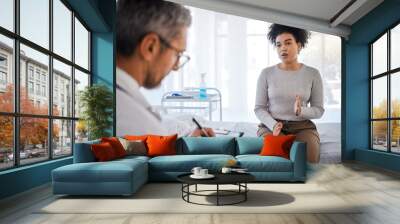 Healthcare, consulting and insurance with a black woman patient sitting in a hospital with her doctor. Medical, consultant and insurance with a female talking to a medicine professional for diagnosis Wall mural