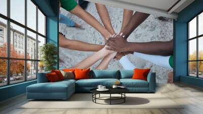 Teamwork, support and volunteer with hands of people from top at beach for sustainability, environment or climate change. Community, earth day or diversity with friends for recycling, charity or goal Wall mural