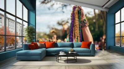 A person holding a handful of colorful Mardi Gras beads in the air  Wall mural