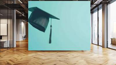 Black graduation cap with tassel isolated on blue background. Wall mural