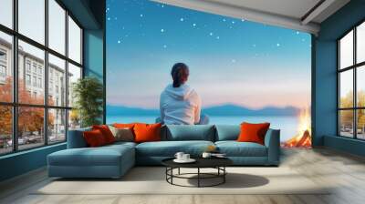 Woman meditating by a campfire under a starry night sky. Wall mural