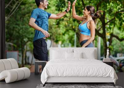 That workout was so worth it. Shot of a sporty young couple high fiving in mid-air while exercising outdoors. Wall mural