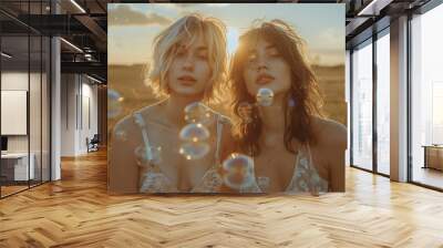 Two young women blowing bubbles at sunset in a countryside field Wall mural