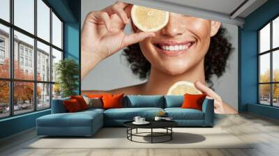 Face, skincare and woman with lemon in studio isolated on a gray background. Fruit, organic cosmetics and happy female model holding lemons for healthy diet, vitamin c or minerals, wellness or beauty Wall mural