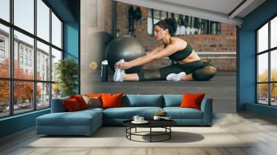 Fitness, exercise and a woman stretching at gym during warm up workout and training for health and wellness. Sports female or athlete on ground to stretch legs to be flexible, balance and healthy Wall mural