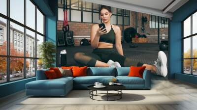 Fitness, phone and woman at gym for a workout, training and body wellness with a mobile app. Young sports female with smartphone for progress, performance and communication for a healthy lifestyle Wall mural