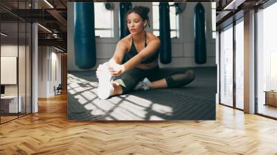 Fitness, stretching and a woman at gym for a warm up workout, training and body wellness with exercise. Young sports female or athlete on floor to stretch legs for strong muscle, balance and energy Wall mural