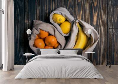 fresh fruits in recyclable eco bags on wooden table, top view Wall mural