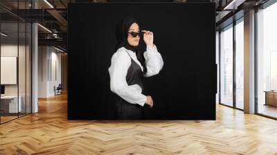 Happy young Asian Muslim woman with a happy face wearing glasses isolated on black background. Wall mural