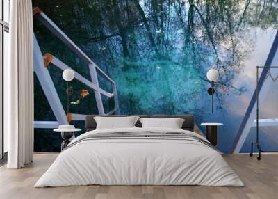 Wooden staircase leading to clear blue water outdoors. Wall mural