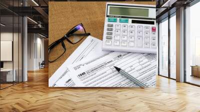 1040 Tax Return document form on a burlap mat table with calculator and glasses Wall mural