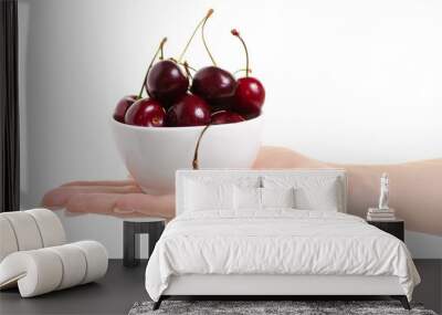 Cherries in a bowl in hands on white background isolation Wall mural