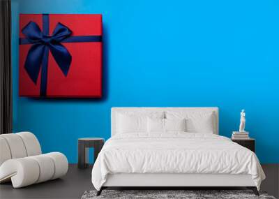 Red gift box with blue ribbon on a blue background Wall mural