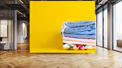 Stack folded colorful clothing summer on yellow background Wall mural