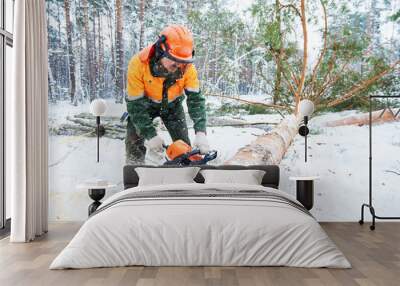 Lumberjack cutting tree in snow winter forest Wall mural