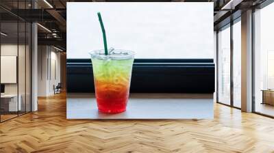 Beverage juicy soft drink in summer concept. Freshness mix sweet fruity soda with splash ice in plastic glass with straw on the table bar over natural background. Wall mural