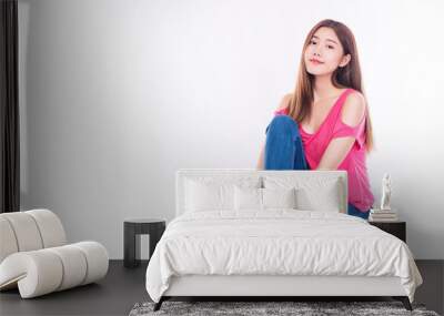 Joyful young woman with long hair wear pink t-shirt showing palm hand while sitting on chair over isolated against white background. Wall mural