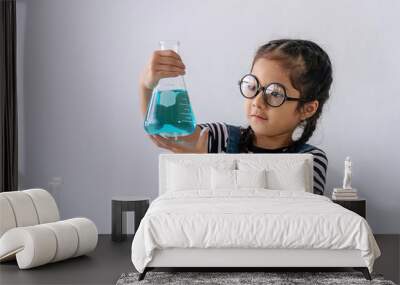 Little 6s cute girl with microscope holding laboratory bottle with water experiment study scientists at school. Education science concept. Wall mural