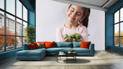 Happy little girl eating fresh vegetables. A portrait on a white background.  Wall mural