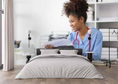 African female doctor in office doing paperwork and writing prescriptions. Wall mural