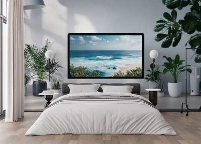 A sleek home office setup features a computer displaying a serene ocean view, with plants and natural light enhancing the tranquil workspace. Wall mural