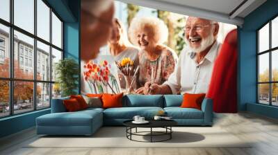 A group of senior citizens engaged in artistic activities, activities for seniors concept. men and women enjoy painting with a brush, sitting around the table, having a good time together Wall mural