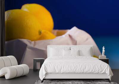 Fresh ripe lemons in paper bag on blue table background Wall mural