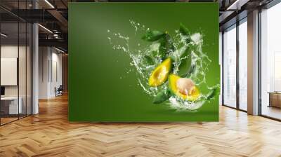 Water splashing on Fresh Sliced Green avocado over the Green background. Wall mural