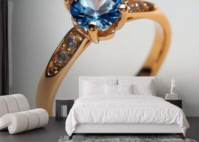 A close-up of a gold engagement ring adorned with a blue gemstone and smaller clear crystals, perfect for use in jewelry advertisements, bridal magazines, or romantic event promotions, Wall mural