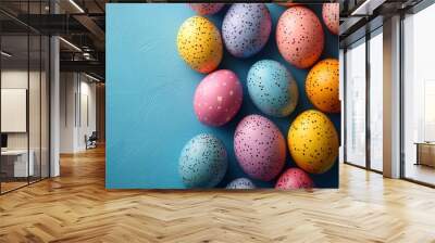 A vibrant assortment of colorful, speckled Easter eggs against a blue textured background perfect for Easter-themed promotions, holiday greeting cards, and children's crafts, Wall mural