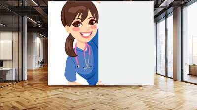 Cute happy young professional nurse peeking out of a blank billboard Wall mural