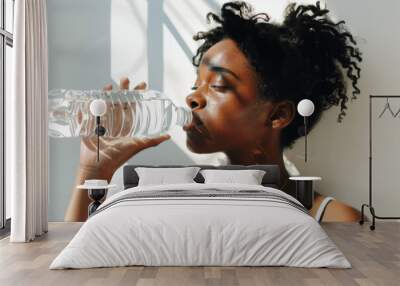 A black woman hydrating with a bottle of water in the sunlight after exercising.

 Wall mural