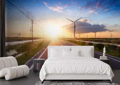 Wind turbines on landscape along empty road against sky Wall mural