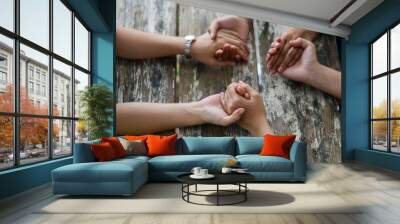 Group of people Praying Hands Over The Bible On Wooden Desk Wall mural