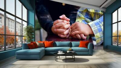 Little sister praying with her baby brother Two people are praying together over holy bible on wooden table Wall mural