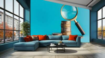 Stack of coins and magnifying glass on blue background, investment analysis concept Wall mural