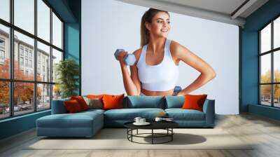 Adult beautiful woman working out over light background Wall mural