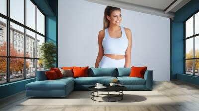 Adult beautiful woman working out over light background Wall mural