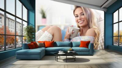 Adult woman sitting on sofa with coffee Wall mural