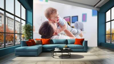 happy mother playing with baby boy at home Wall mural